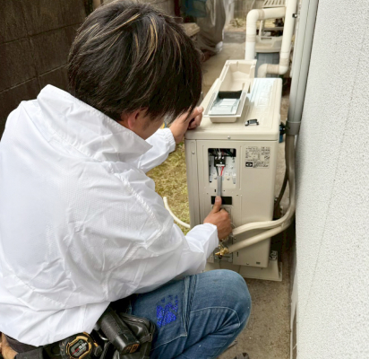 室外機を修理中のスタッフ