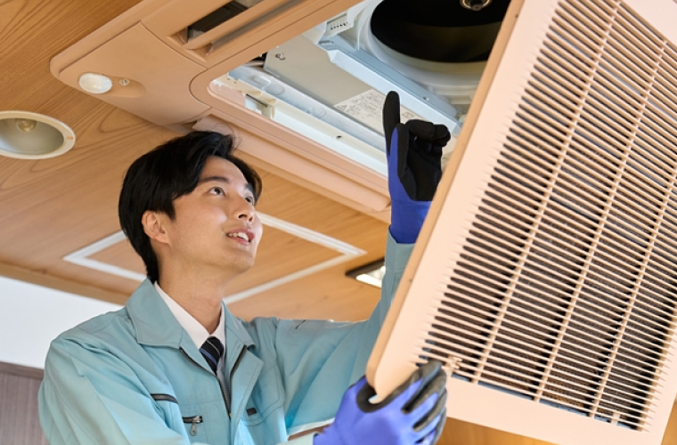 天井埋込エアコンを開けて中を確認しているスタッフ